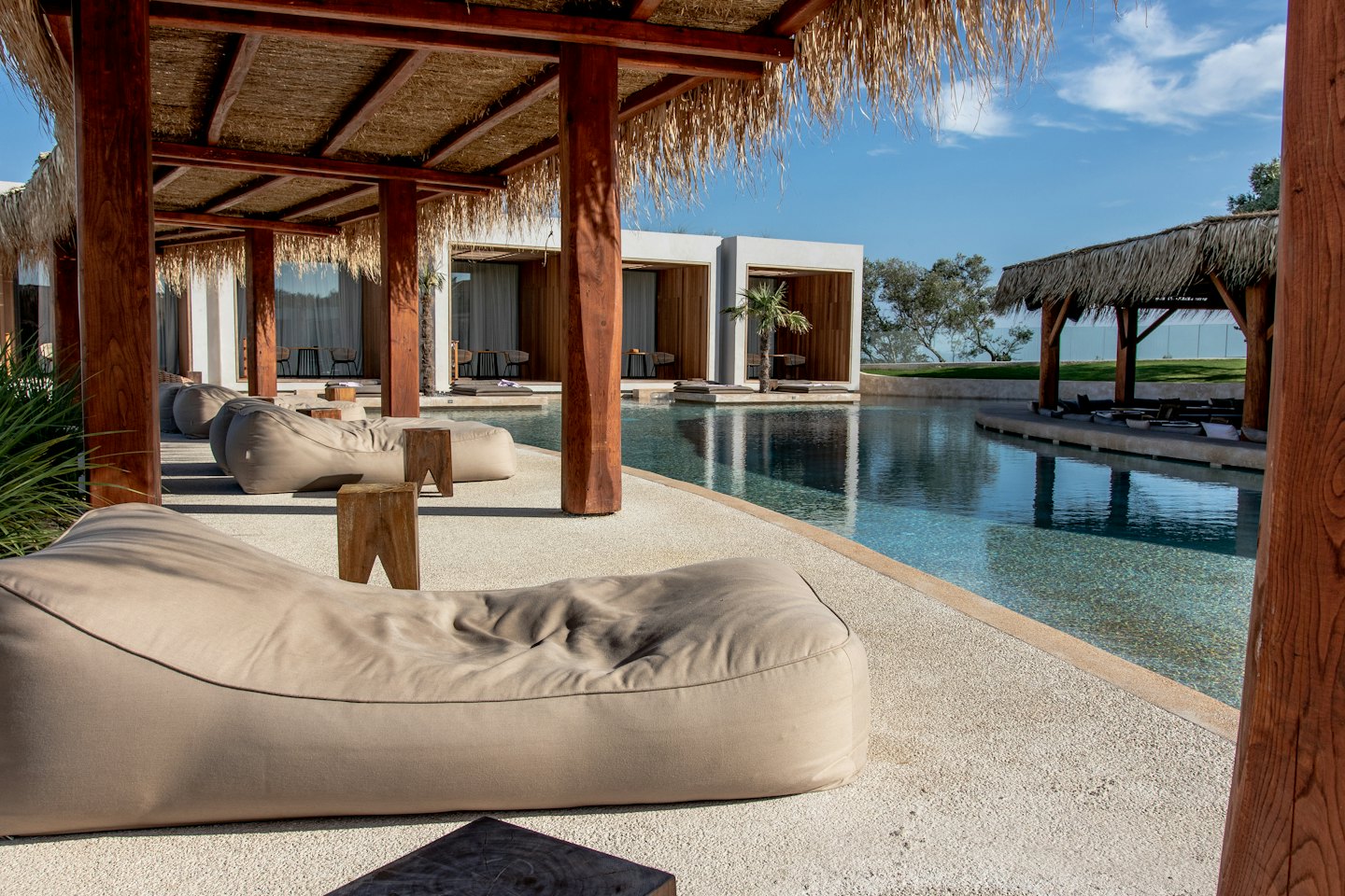 Tranquil resort pool with lounge chairs and thatched roof structures.
