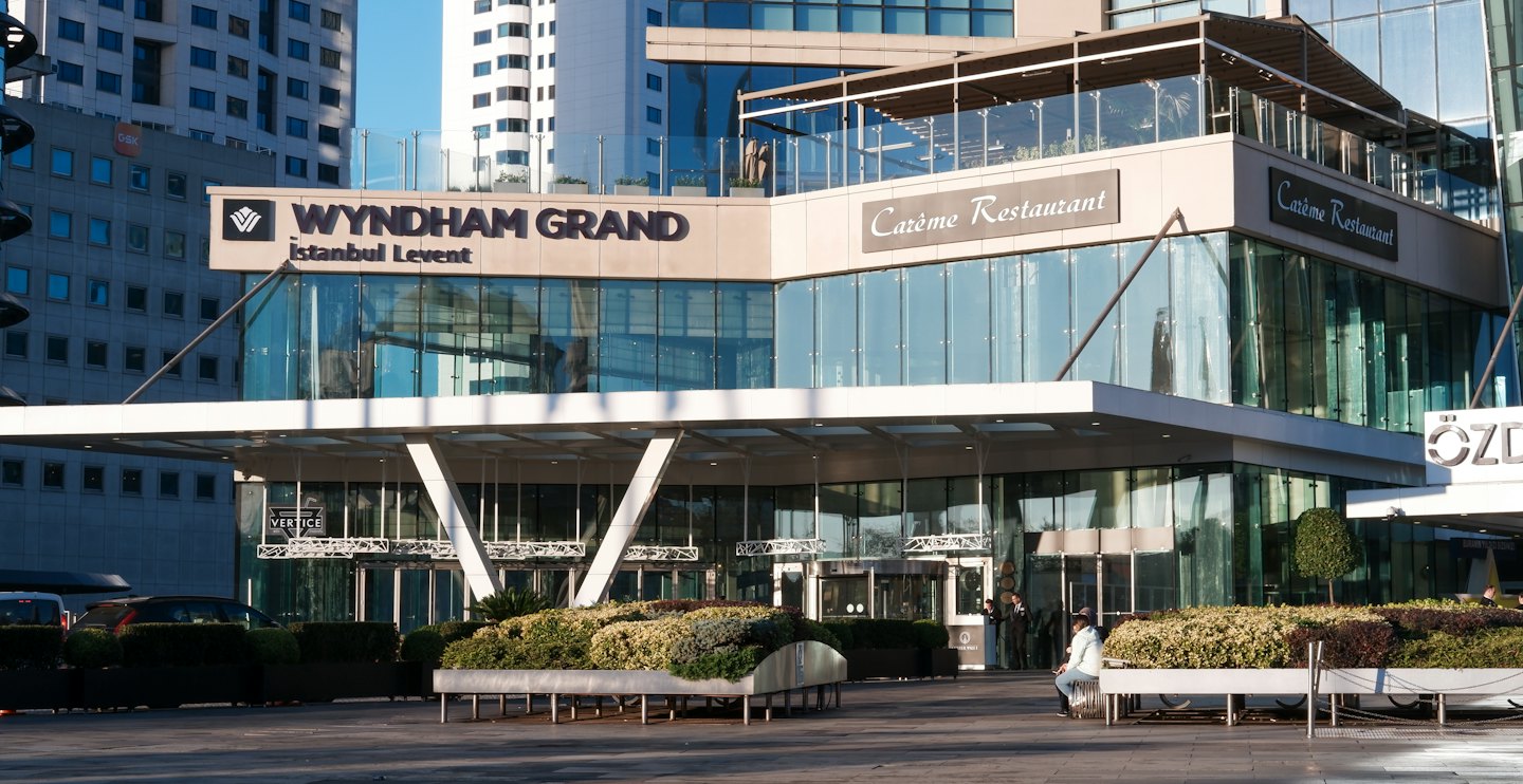 Modern hotel entrance with glass windows and outdoor seating.